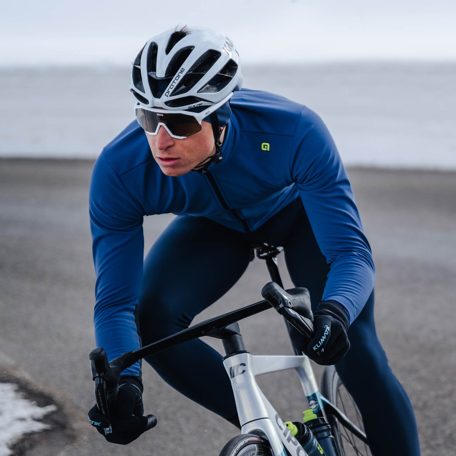 Cyclist in blue jacket and helmet riding a bike on a road with a blurred background