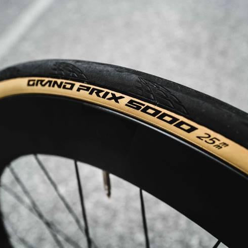 Close-up of a bicycle tire with 'Grand Prix 5000' branding on a blurred road background.